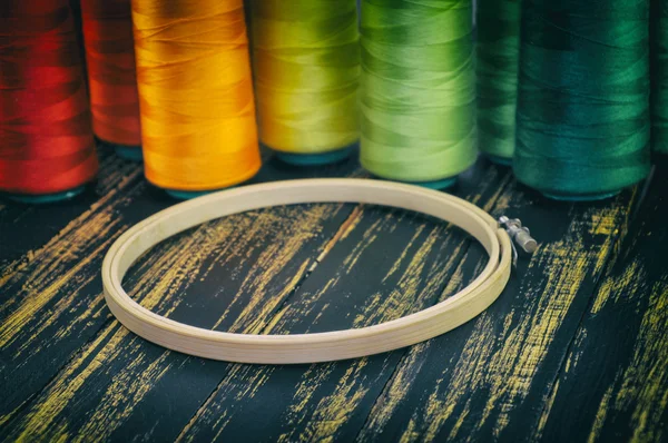 wooden hoop closeup on a background of colorful spools of thread