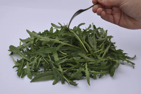 Ruccola och mänskliga handen med en gaffel — Stockfoto