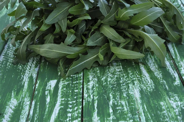 Färsk ruccola på ett träbord gamla gröna — Stockfoto