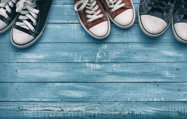 Drie paren van sneakers op een houten blauwe achtergrond — Stockfoto