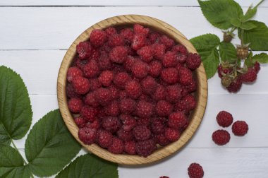 Yeşil yaprakları ile ahşap bir kase taze frambuaz 