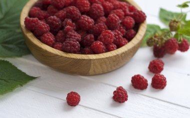 Beyaz ahşap bir masa üzerinde kırmızı olgun ahududu