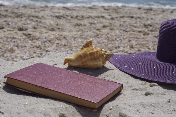 Книга и шляпа на пляже — стоковое фото