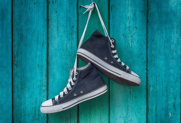 Pair of blue men's sports sneakers hanging from a nail on the wa — Stock Photo, Image