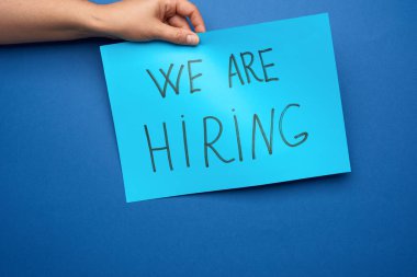 İşe aldığımız yazılı mavi kağıt parçası, küresel krizin arka planına karşı işsizlik kavramı, kovulmuş çalışan, mavi arkaplan 