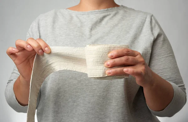 Kobieta Trzyma Ręku Biały Elastyczny Bandaż Dla Ciała Szare Tło — Zdjęcie stockowe