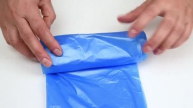 İki kadın el mavi çöp torbalarıyla bir rulo çevirir.