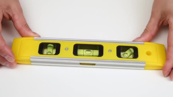 Tangan Wanita Memegang Tingkat Plastik Kuning Untuk Konstruksi Pada Latar — Stok Video