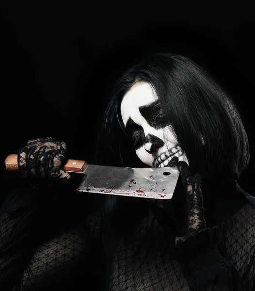黒の服と頭蓋骨のメイクの女性黒の背景ハロウィンのカーニバルの衣装手に血の縞のナイフを持っている — ストック写真