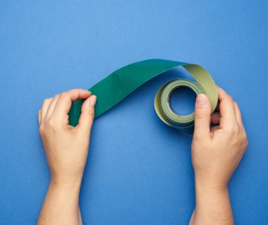 El ele tutuşun yeşil rulo kağıt yapışkan bant mavi arkaplan, üst görünüm