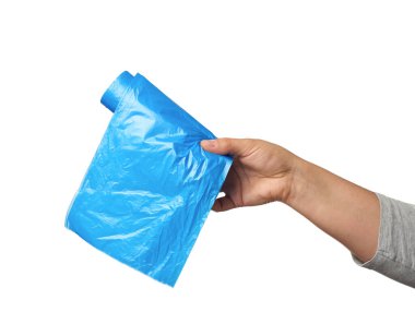 Kadın eli çöpler için mavi plastik poşetler tutuyor, vücudun bir parçası beyaz arka planda izole edilmiş.