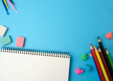 Boş beyaz çarşaflı defter, çok renkli tahta kalemler, üst görünüm, okula dönüş konsepti, düz yatış.