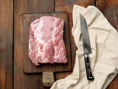 Bıçak ve çiğ domuz filetosu ahşap bir kesme tahtasının üzerinde, üst manzara