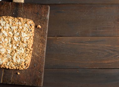 Ahşap tahtada meyve dolu fırınlanmış dikdörtgen pasta, kahverengi arkaplan, üst manzara, kopyalama alanı