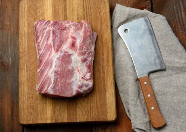 Bıçak ve çiğ domuz filetosu ahşap bir kesme tahtasının üzerinde, üst manzara