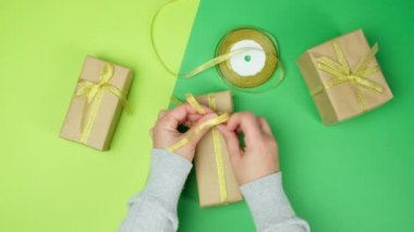 Kadın hediyeleri kahverengi kağıda ve altın kurdeleye koyar, yeşil arka plan, üst manzara