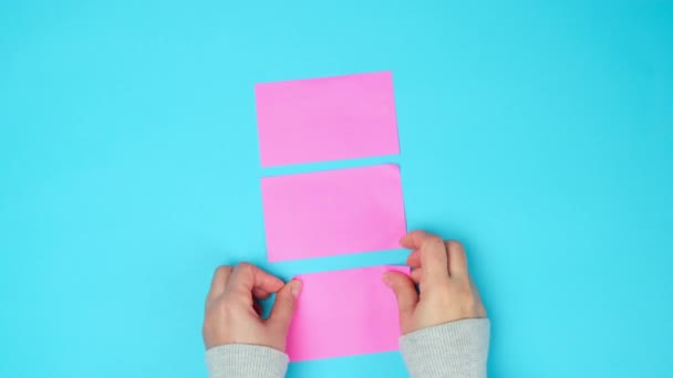 Vrouwelijke Hand Lijmen Roze Papier Blanco Stickers Een Blauwe Achtergrond — Stockvideo