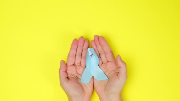 Female Hand Holds Blue Silk Ribbon Shape Loop Yellow Background — Stock Video