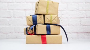 Kahverengi kağıda sarılı dikdörtgen bir kutu ve ipek bir kurdeleyle bağlanmış beyaz bir arka planda hediye..