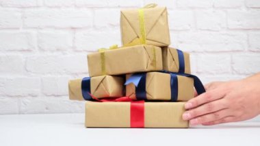 Kahverengi kağıda sarılı dikdörtgen bir kutu ve ipek bir kurdeleyle bağlanmış beyaz bir arka planda hediye..