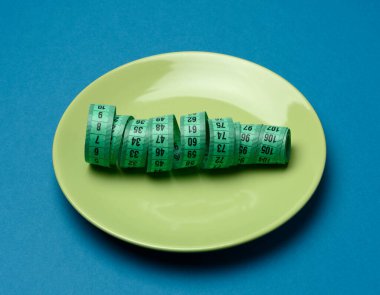 yeşil yuvarlak plaka ve mavi arka planda yeşil mezura, kilo kaybı konsepti, düz yatış