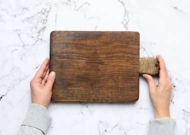 İki kadın eli boş eski kahverengi dikdörtgen tahta bir kesme tahtası, beyaz arka plan, üst görünüm