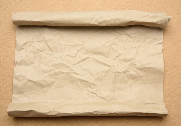 roll of brown parchment paper on a brown background, copy space, top view