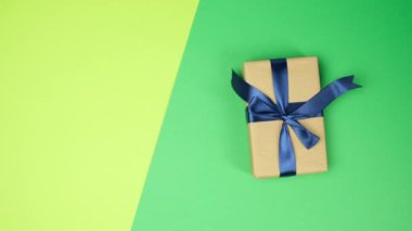 Kadın eli yeşil yüzeye sarılıp mavi kurdeleli hediyeler takar, üst manzara, şenlikli arka plan