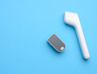 Plastik beyaz elektronik temas olmayan termometre ve kan oksijen ölçer, mavi arkaplan