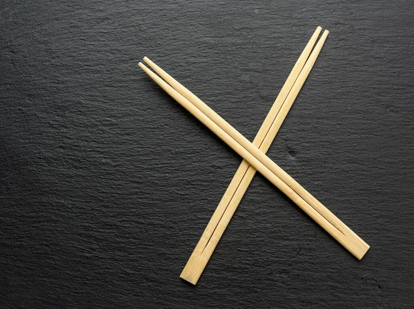 Δύο Ξύλινα Sticks Για Σούσι Μαύρο Φόντο Πάνω Όψη — Φωτογραφία Αρχείου