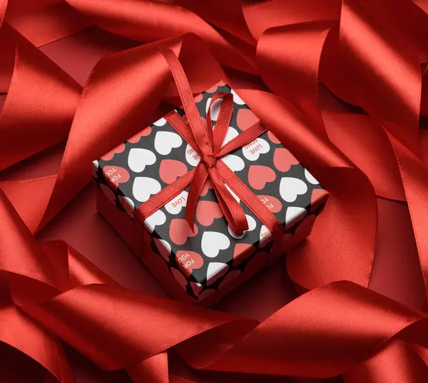Подарочная Коробка Упакована Красную Бумагу Скрученную Шелковую Ленту Красном Фоне — стоковое фото