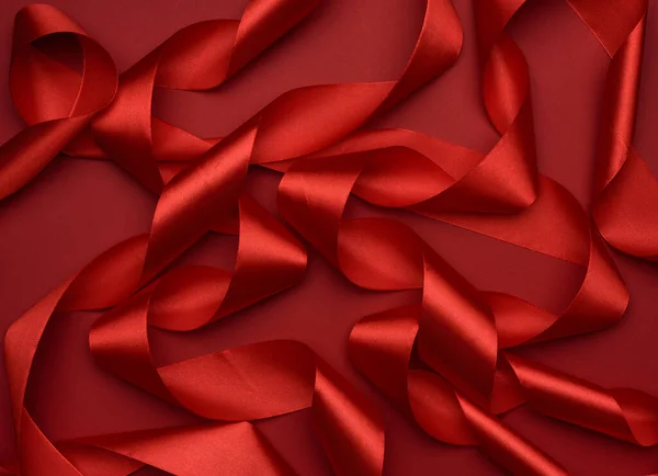 curled red silk ribbon on a red background, festive background