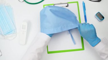 Doktor için kravatlı mavi tekstil tıbbi şapkası, doktorun masasının üst görüntüsü.