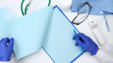 Beyaz önlüklü doktor ve mavi lateks eldivenli doktor iş yerinde mavi boş sayfaları karıştırıyor.