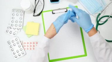 Ellere mavi lateks steril eldiven takma süreci, salgın ve salgın sırasında virüslerden korunma kavramı, beyaz arka plan, üst görünüm