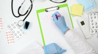 Doktorun elinde mavi lateks eldiven var. Paniği durdurun, terapistin masasına bakın yazıyor.