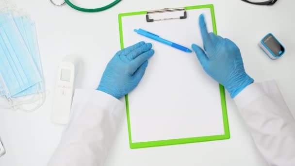 Доктор Белом Халате Голубых Латексных Перчатках Жестикулирует Руками Сидя Белым — стоковое видео