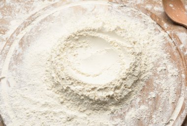 Yuvarlak ahşap bir tahtanın üzerine yığılmış beyaz buğday unu.