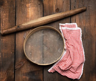 Kaliteli ahşap raptiye ve yuvarlak elek, kırmızı peçete, üst manzara, hamur yapmak için pişirme aletleri