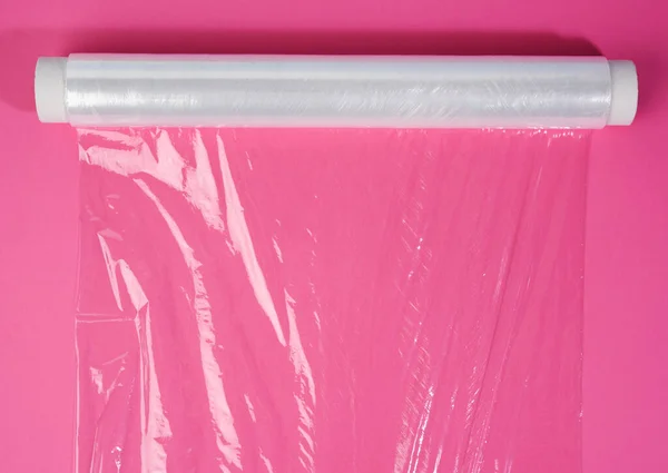 製品のパッケージ化 トップビューのためのピンクの背景に透明リングフィルムのロール — ストック写真