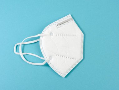 Mavi arka planda beyaz tek kullanımlık tıbbi maske. Virüs bulaşmasından kaynaklanan solunum yolu için kişisel koruyucu ekipman.
