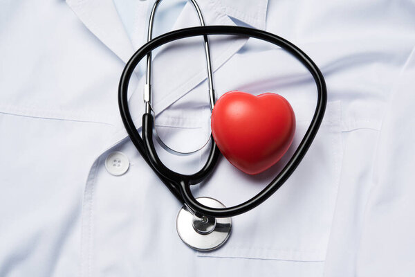медицинский стетоскоп и красное резиновое сердце на белом фоне, вид сверху