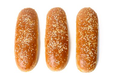 fırında oval sosisli çörek, üzerine susam tohumu serpiştirilmiş ve beyaz arka planda izole edilmiş, üst görünüm.