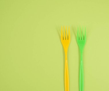 Yeşil arkaplanda plastik çatal yığını, üst görünüm, kopyalama alanı