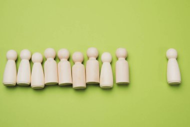 Tahta adamlar yeşil arka planda bir grubun yanında duruyorlar. Liderlik kavramı, takım zorbası.