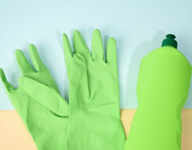 Yeşil lastik eldivenler temizleme ve temizlik sıvısı için mavi arka planda plastik bir şişede, düz bir zemin, üst manzara