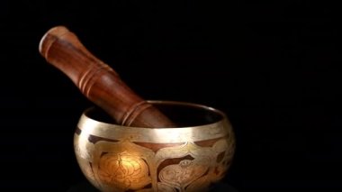 Bakır şarkı kasesi siyah arka planda kendi ekseni etrafında döner. Meditasyon ve alternatif tıp için Tibet müzik aleti
