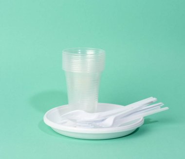 Tek kullanımlık plastik sofra takımı, fincanlar, çatallar ve bıçaklar yeşil arka planda, piknik seti