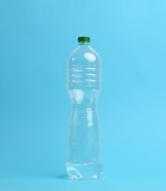 Mavi zemin üzerinde taze su bulunan şeffaf plastik bir şişe.