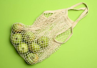 Yeşil arkaplanlı bej renkli tekstil çantası, yeniden kullanılabilir şeyler kavramı, sıfır atık